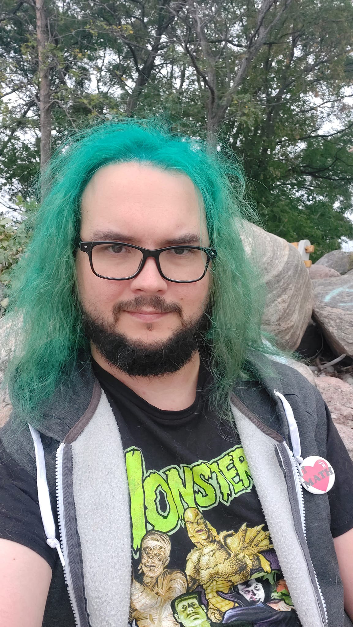 A man with green hair stands outside at a boulder breakwater, photo 2